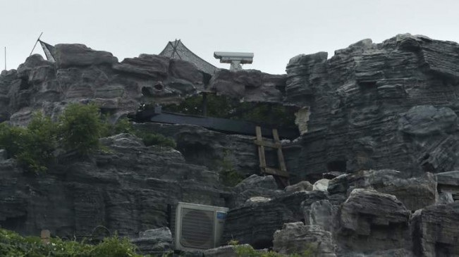 A surveillance camera is seen on the top of a privately built villa, surrounded by imitation rocks, on the rooftop of a 26-storey residential block in Beijing